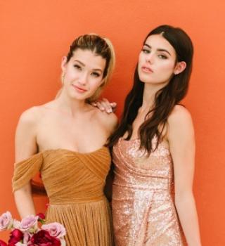 Two woman standing in front of orange wall